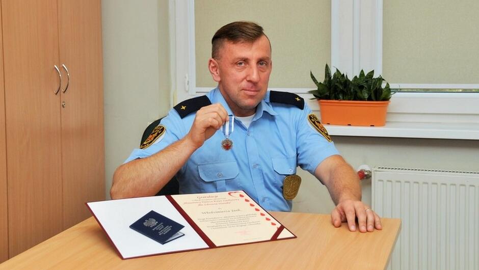 strażnik Włodzimierz Jank z medalem HDK okno szafa stół dyplom honorowego dawcy krwi kwiat na parapecie kaloryfer