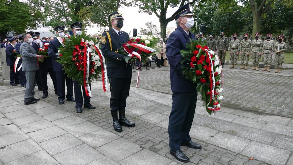 pocztowcy i straznik z wieńcami żołnierze zaproszeni goście drzewa mogiły na cmentarzu.JPG
