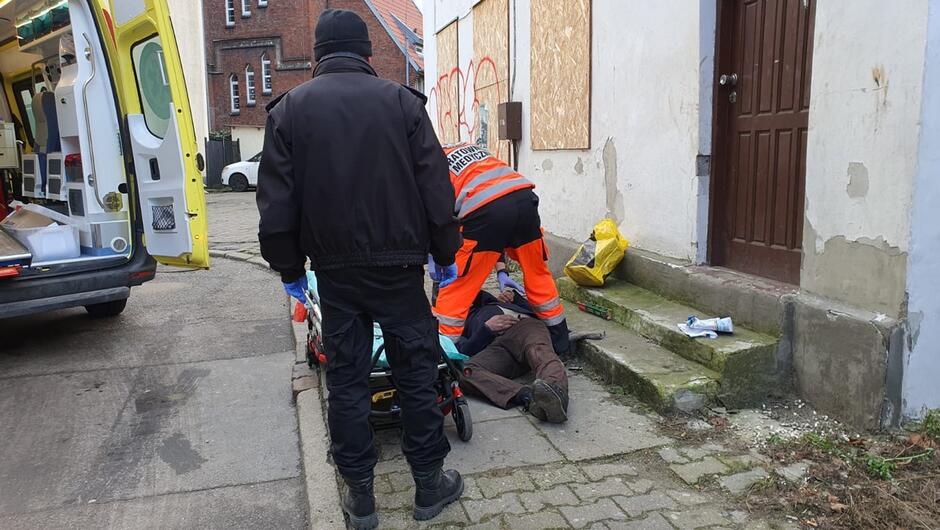 strażnik miejski ratownik medyczny udzielający pomocy wnętrze karetki budynki mieszkalne